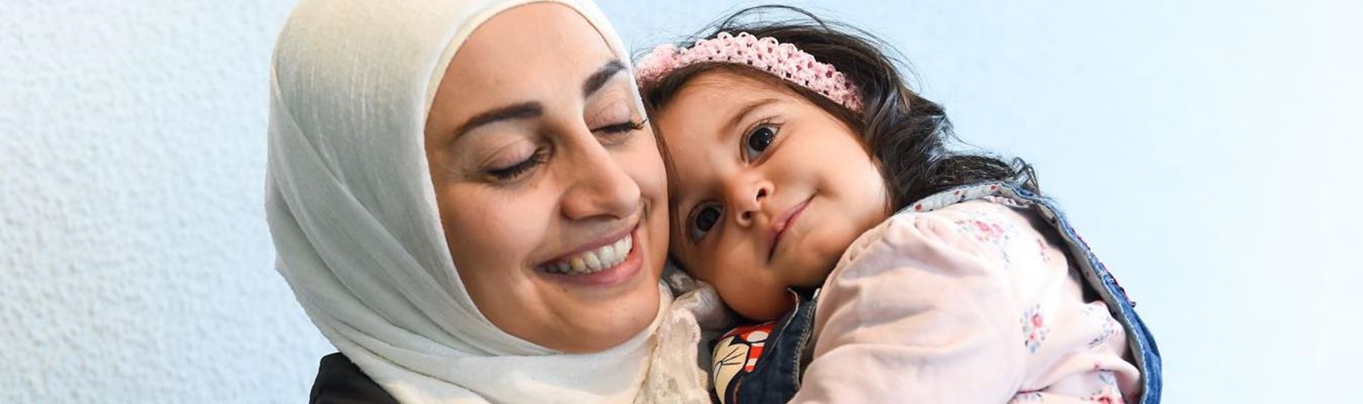 Frau mit Kopftuch und kleinem Mädchen auf dem Arm