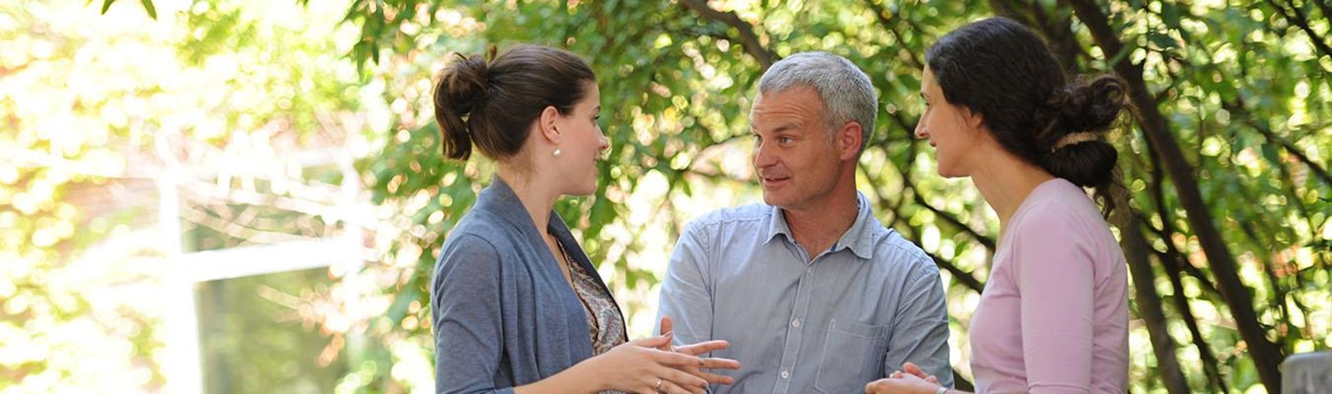 Diskussion zwischen zwei Frauen und einem Mann im Freien