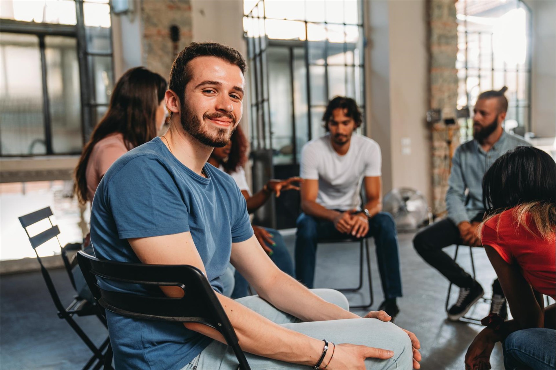 Ein Mann sitzt vor einem Stuhlkreis. 