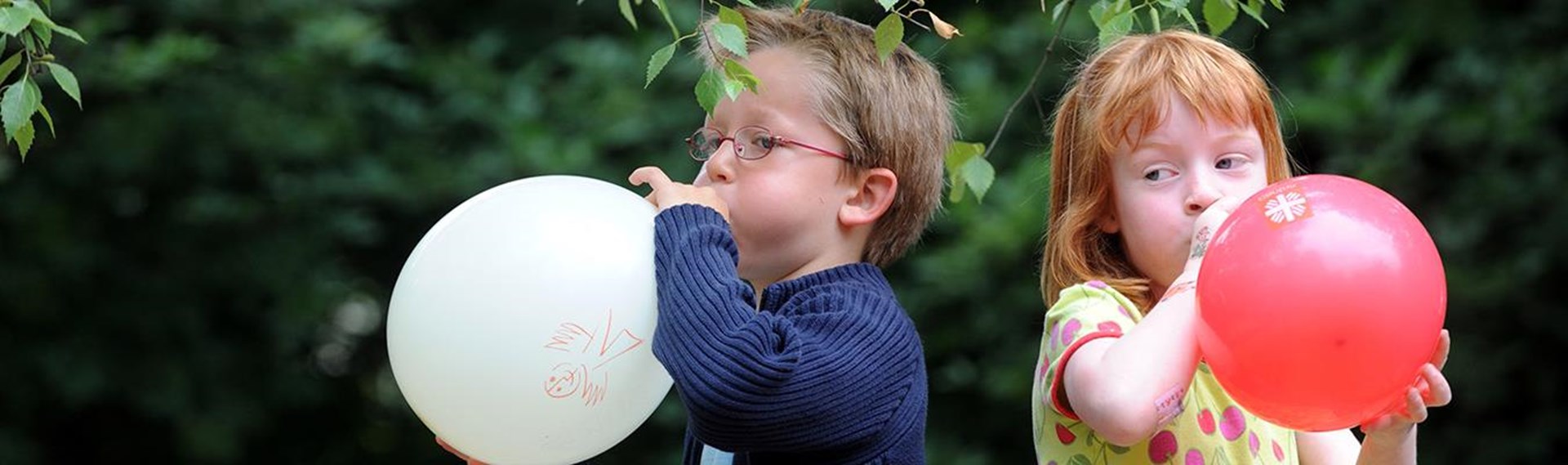 Junge und Mädchen mit Caritas-Luftballons