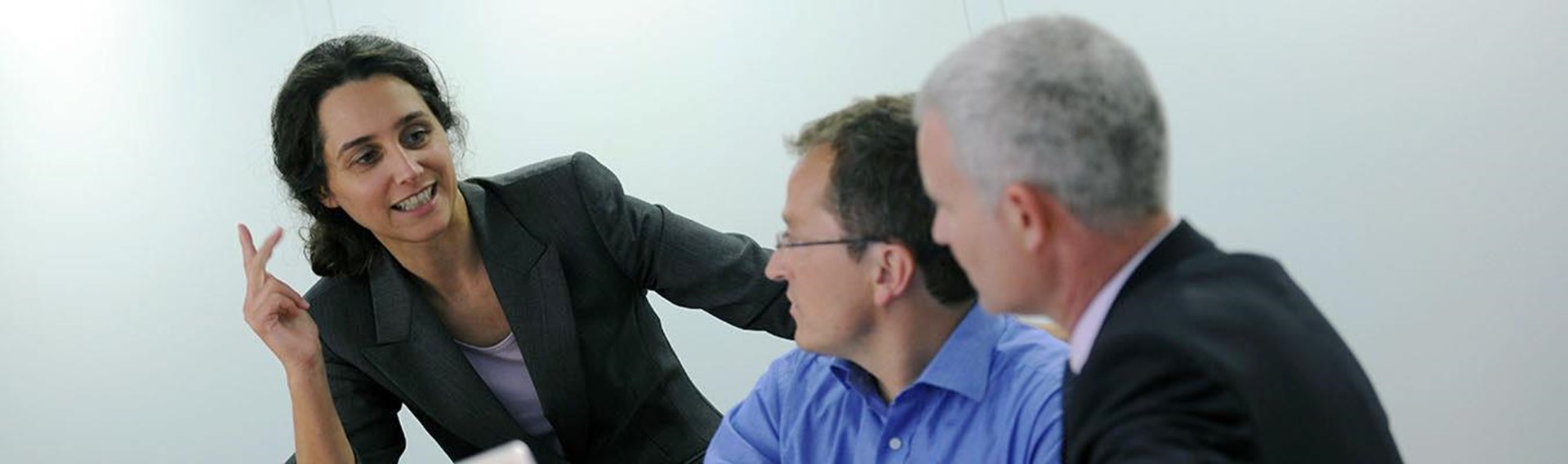 Frau diskutiert mit zwei Männern in Anzug