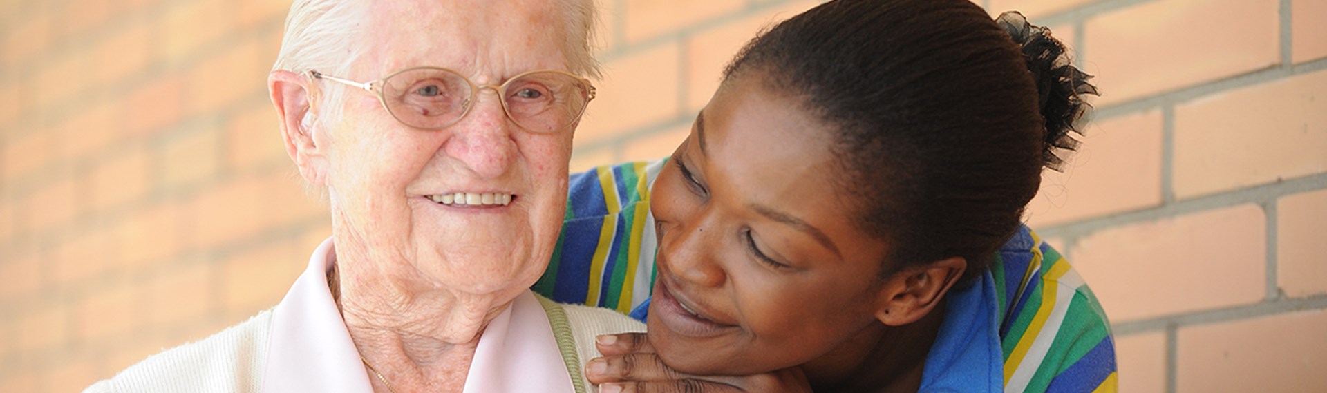 Pflegerin umarmt ältere Frau