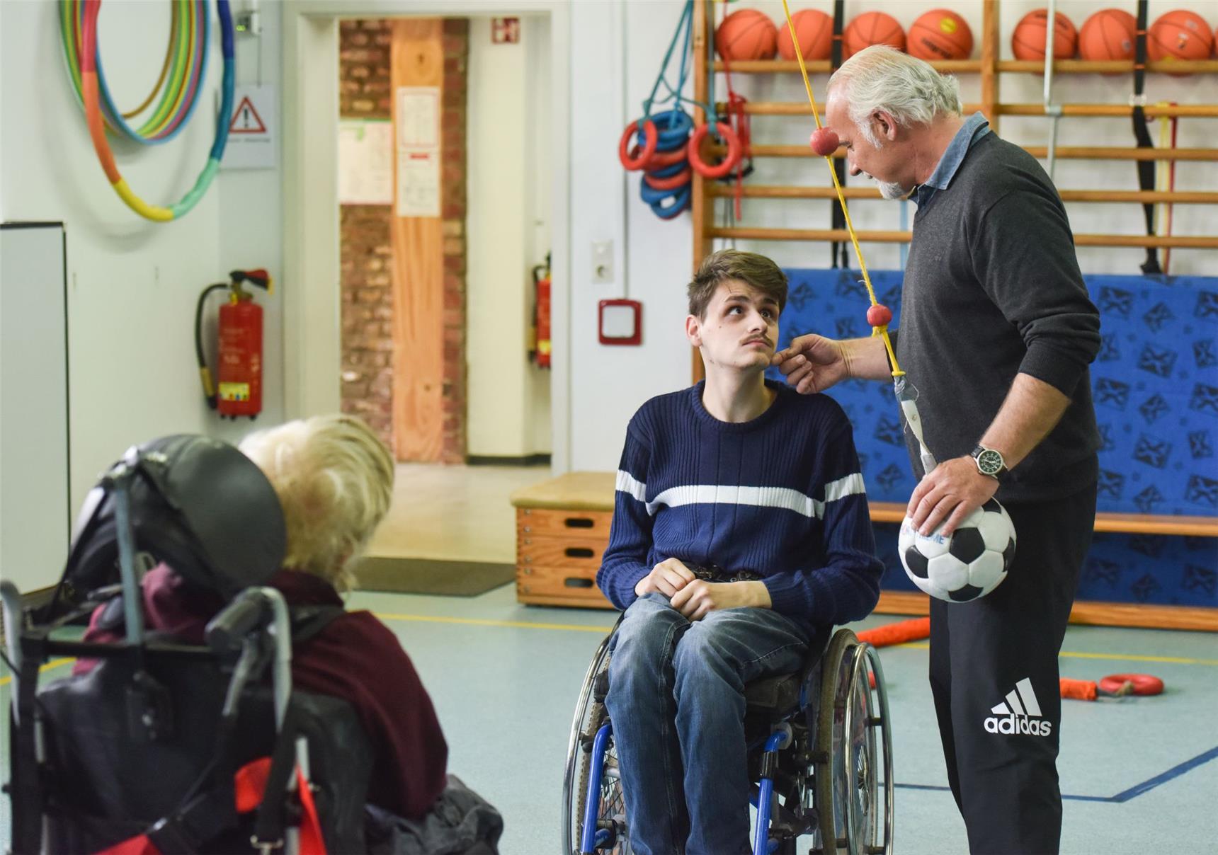 Zwei Menschen mit Behinderung und ein Betreuer in der Sporthalle