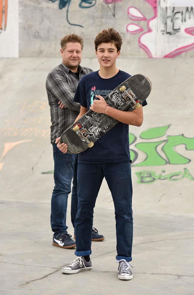 Ein Quartiersarbeiter und ein Junge mit einem Skateboard stehen in einem Skatepark