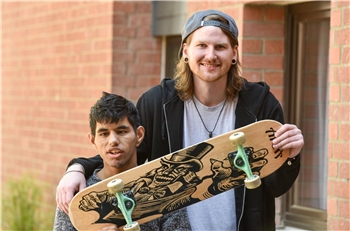 Junge mit Behinderung mit Freund Junge mit Behinderung steht neben Freund, der seinen Arm um ihn legt