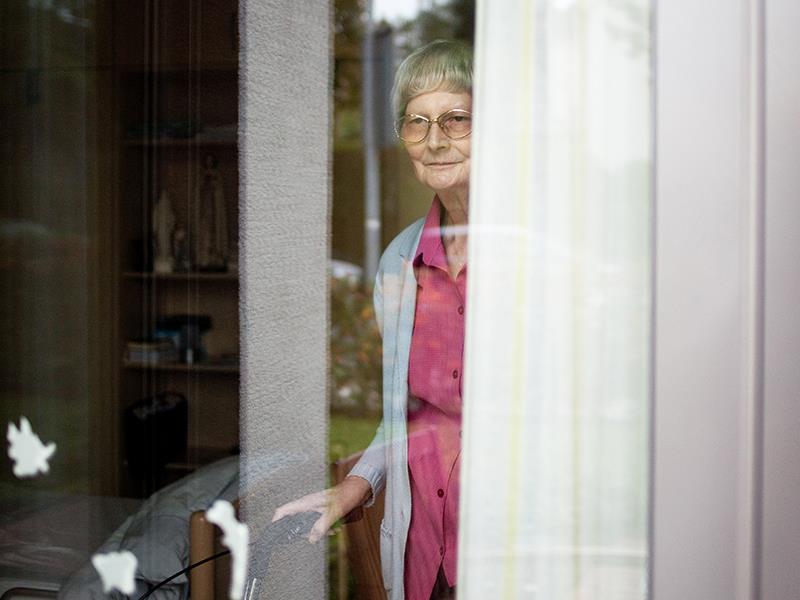 Alte Frau schaut aus dem Fenster.