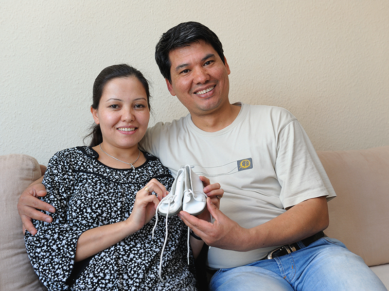 Paar auf Sofa, Babyschuhe auf Tisch