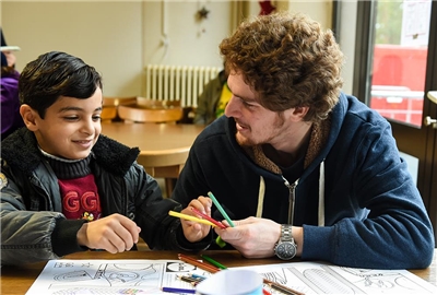 Sozialpädagogische/- r Assistent/- in Mann mit Kind in Schulzimmer