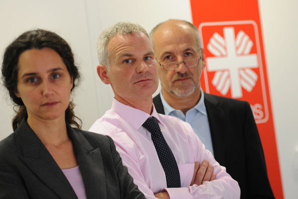 Zwei Männer stehen hinter einer Frau