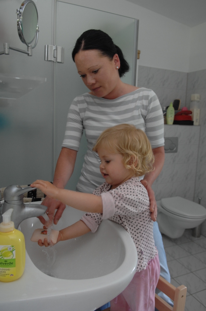 Frau mit Kleinkind am Hände waschen