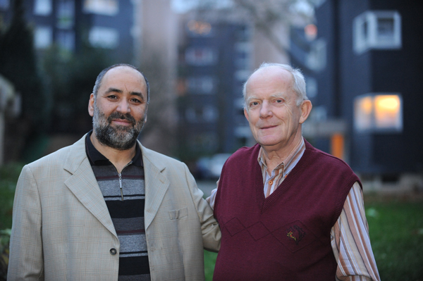 Zwei ätere Männer vor einer Wohnsiedlung am Abend