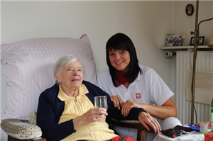 Pflegerin mit trinkender Dame Pflegerin reicht älterer Dame ein Glas