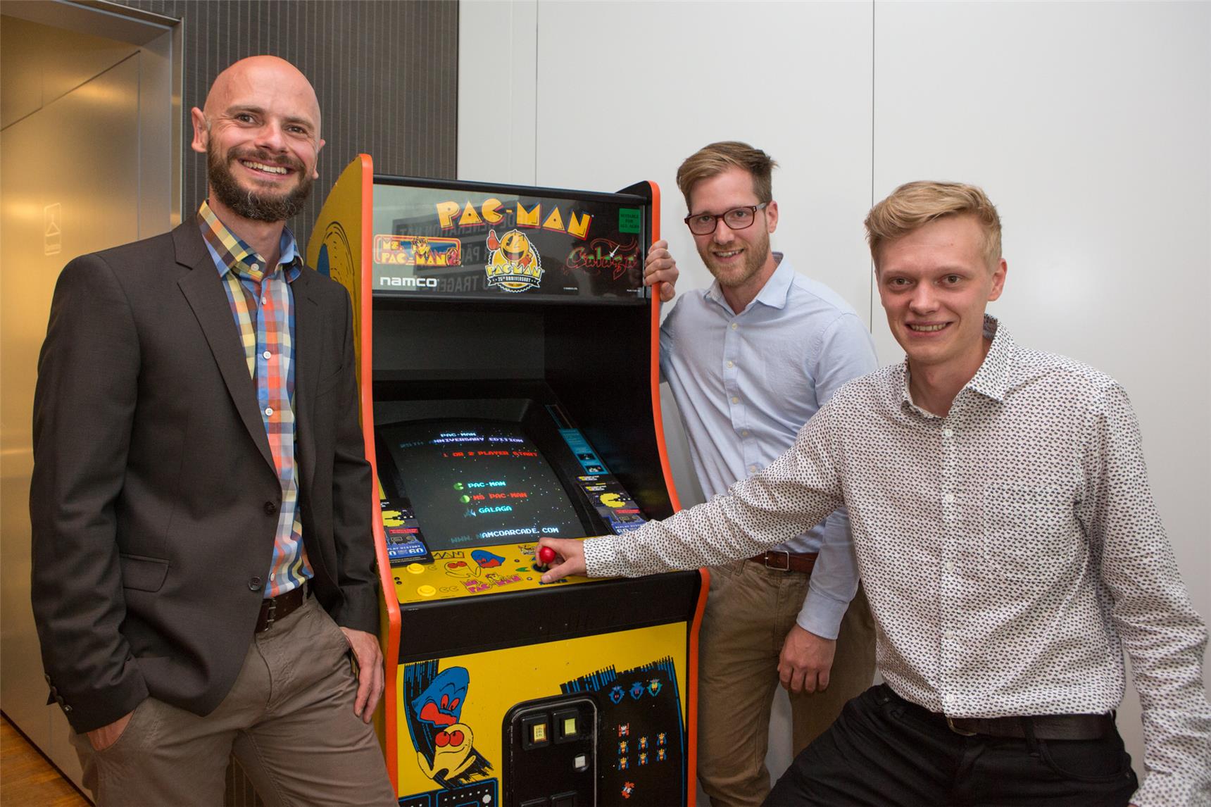 Drei Männer mit Glücksspielautomat.