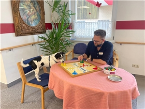 Benjamin Gronau sitzt an einem Tisch im katholischen Pflegeheim Maria im Tann und spielt Mensch Ärgere Dich Nicht.