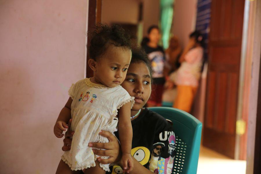 Ein junges Mädchen hält ein Baby in die Luft