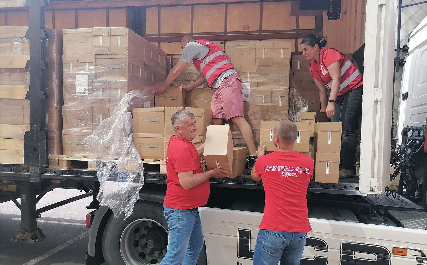 Caritas-Mitarbeitende verteilen Trinkwasser nach der Zerstörung des Kachowka-Staudamms.
