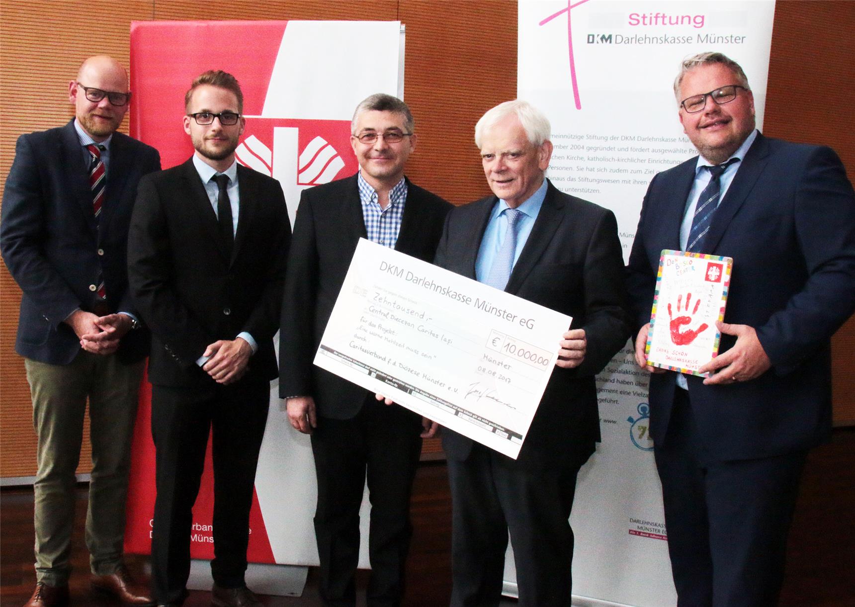 Auf dem Foto stehen mehrere Männer mit einem übergroßen Scheck