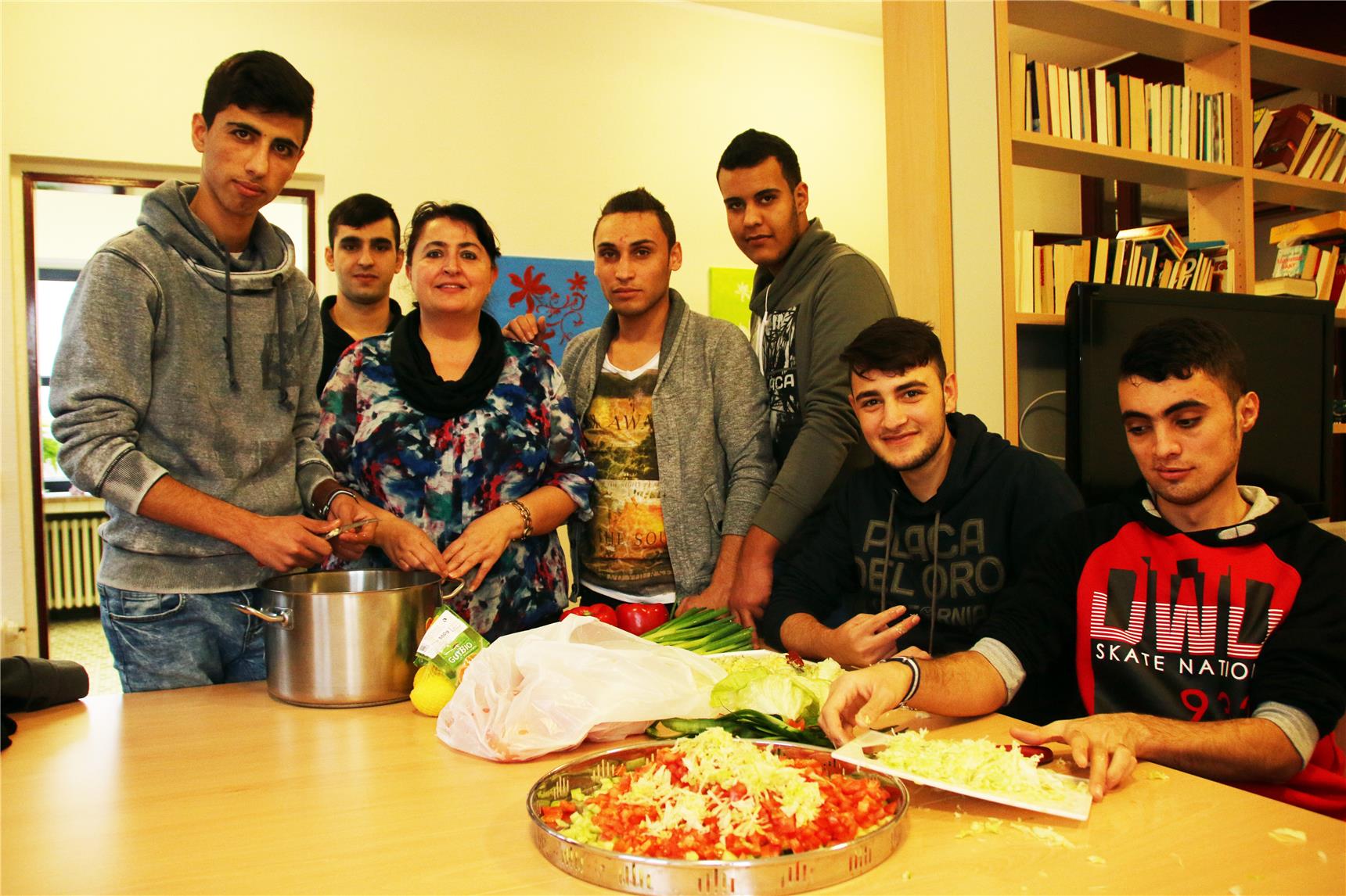 Mehre Menschen sitzen und stehen an einem Tisch