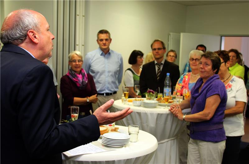 Das Bild zeigt mehrere Personen in einem Raum. Zwischen ihnen stehen Stehtische.