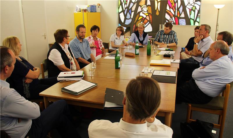 Mehrere Personen sitzen in einem Raum an einem großen Tisch