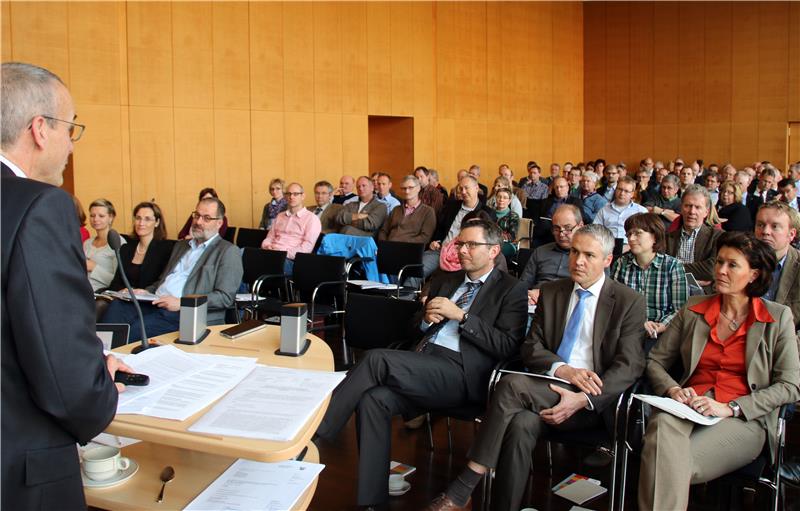 Der Moderator steht vor einer Gruppe sitzender Leute.