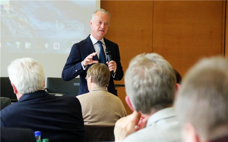 Man sieht Dr. Dr. Thomas Rusche hinten im Bild stehen, wie er seinen Vortrag hält vor den Teilnehmern, die im Vordergrund des Bildes sitzen.