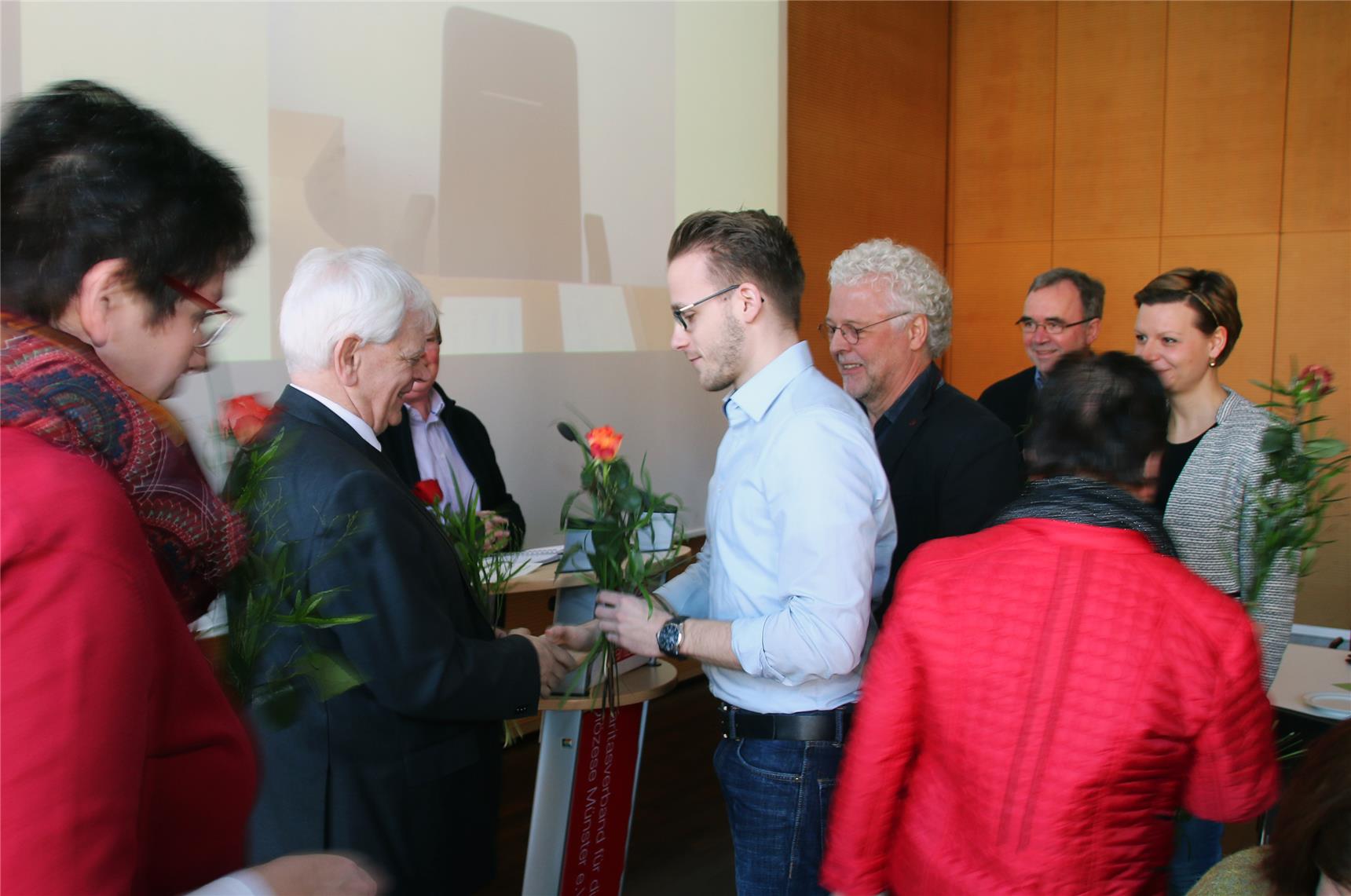 Auf dem Bild überreicht ein Mitarbeiter eine Rose