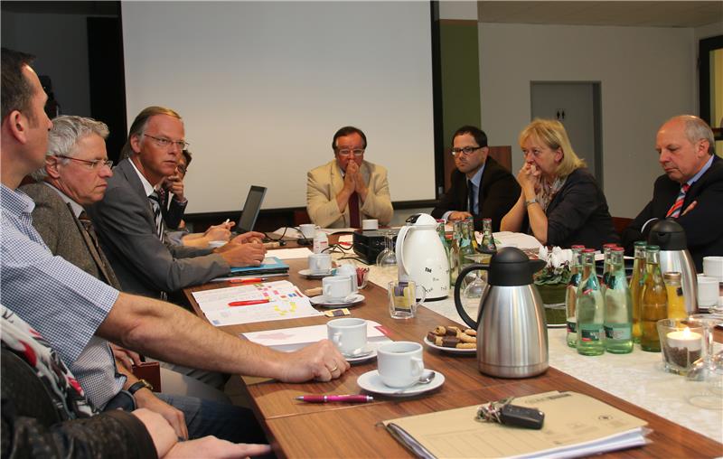 Das Foto zeigt eine Gruppe Menschen, die um einen Tisch sitzt.