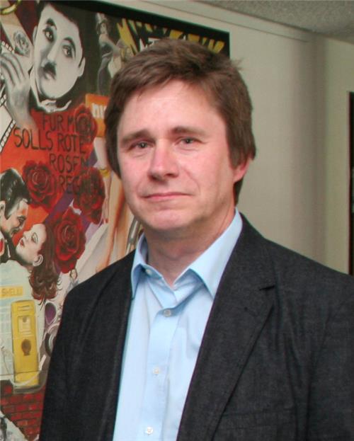 Auf dem Foto steht Dr. Wingenfeld vor einem Bild