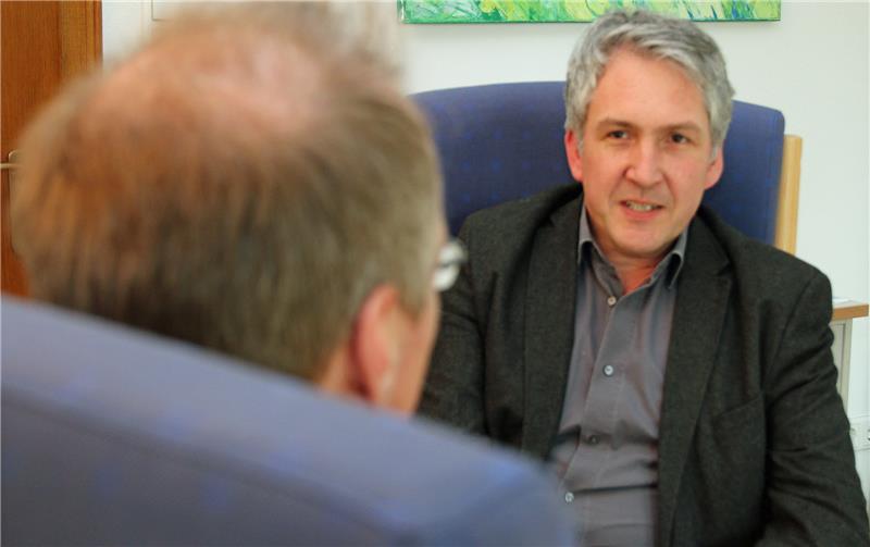 Das Bild zeigt zwei Männer, die auf Stühlen sitzen.