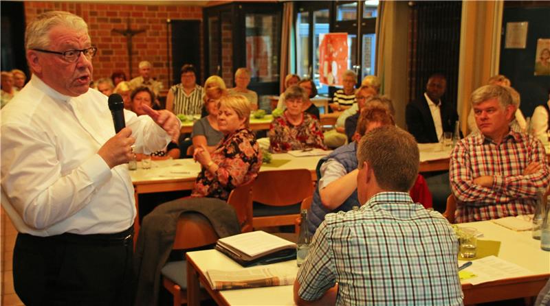 Ein Mann spricht durch ein Mikrofon zum Publikum.