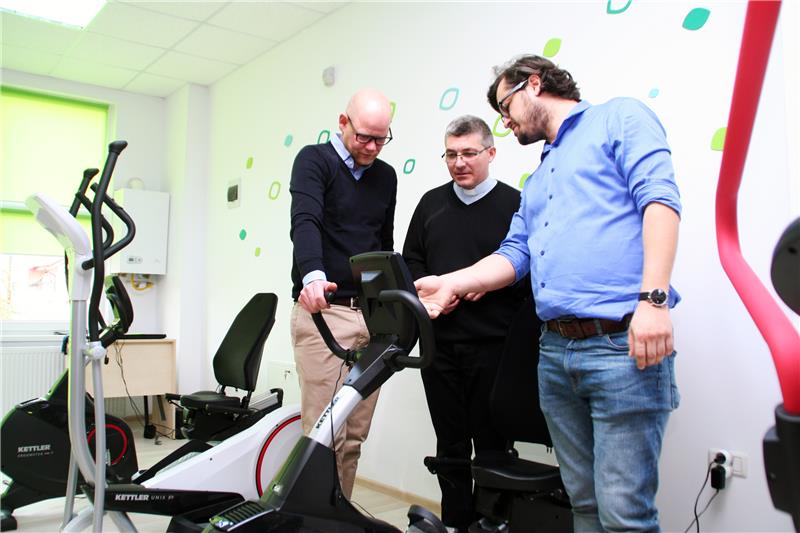 Drei Personen schauen sich ein Sportgerät an.