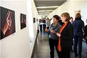 002-2016 Ausstellung Gebärdensprache Das Foto zeigt Menschen auf einem langen Flur, die Fotos betrachten.
