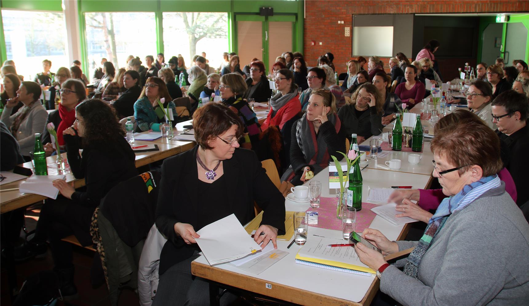 Auf dem Bild sind mehere Personen an Tischen zu sehen