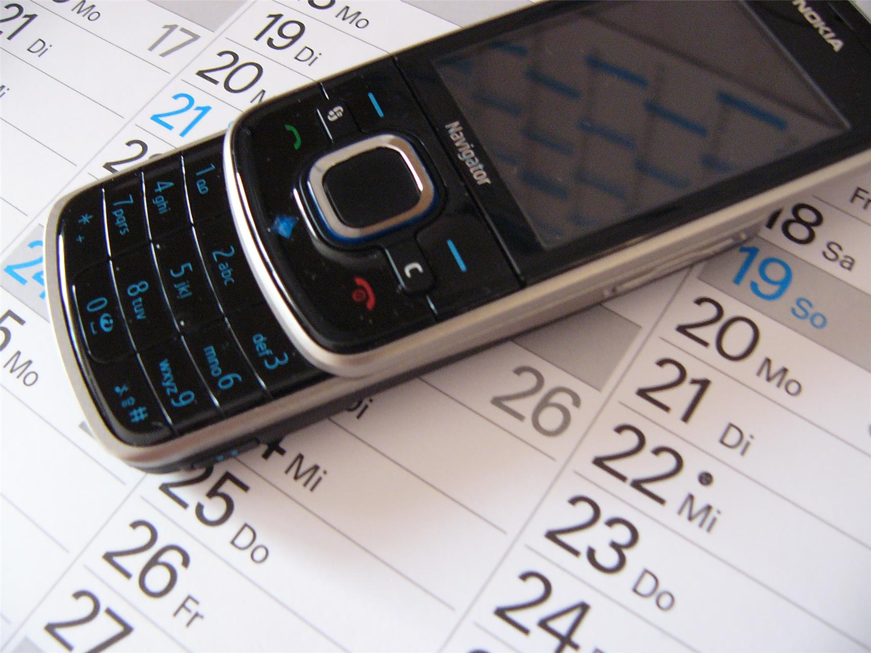 Das Foto zeigt ein Handy, das auf einem Kalenderausschnitt liegt.