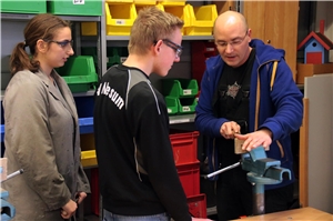 067-2017_Bessere Karten für die Vermittlung Der Ausbilder steht mit zwei Auszubildenden im Werkraum und feilt.