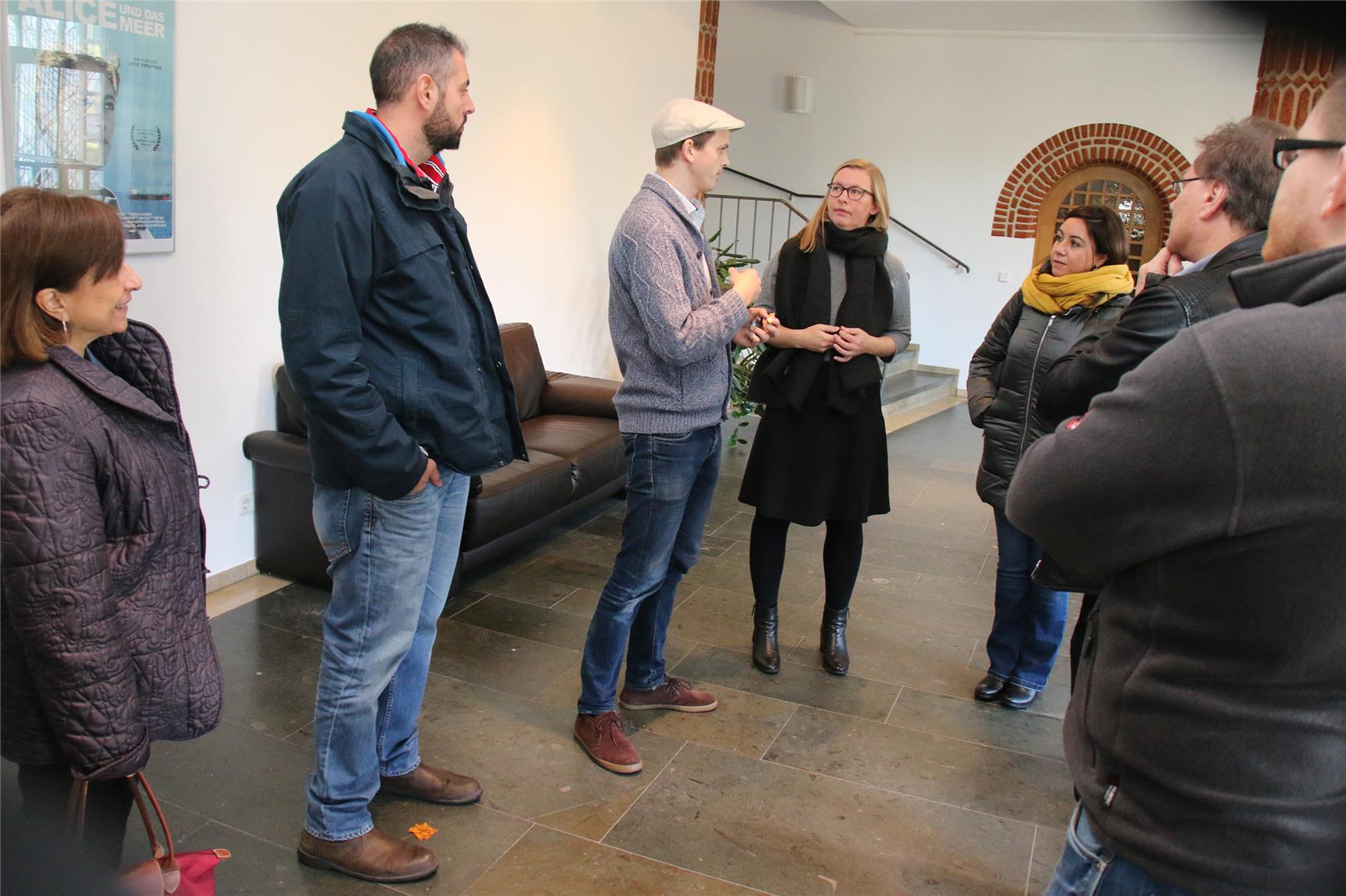 Das Foto zeigt eine Gruppe von Menschen, die im Foyer eines Gebäude zusammensteht.