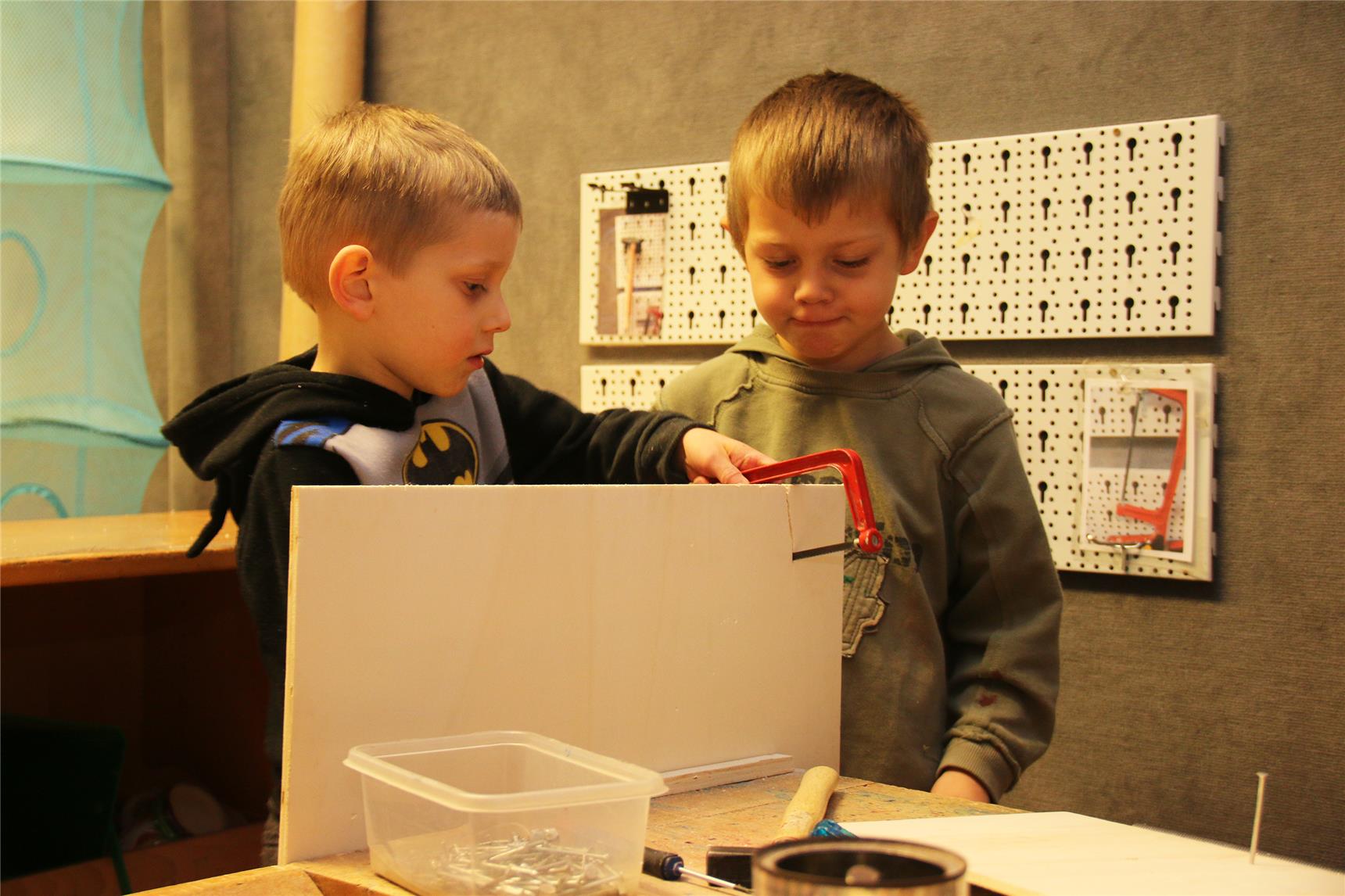 Auf dem Foto basteln zwei Jungs an einer Pappe