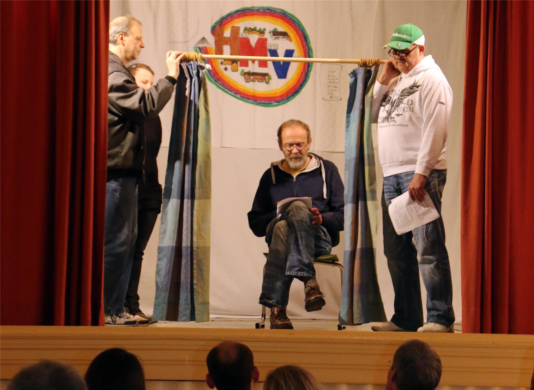 Das Foto zeigt eine kleine Gruppe von Menschen auf einer Bühne, die ein Theaterstück aufführen.