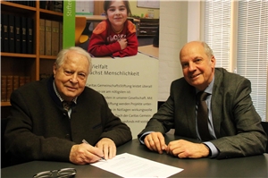 017-2019 Stiftungsfonds Das Foto zeigt zwei Männer, die an einem Tisch sitzen, auf dem ein Vertrag liegt.