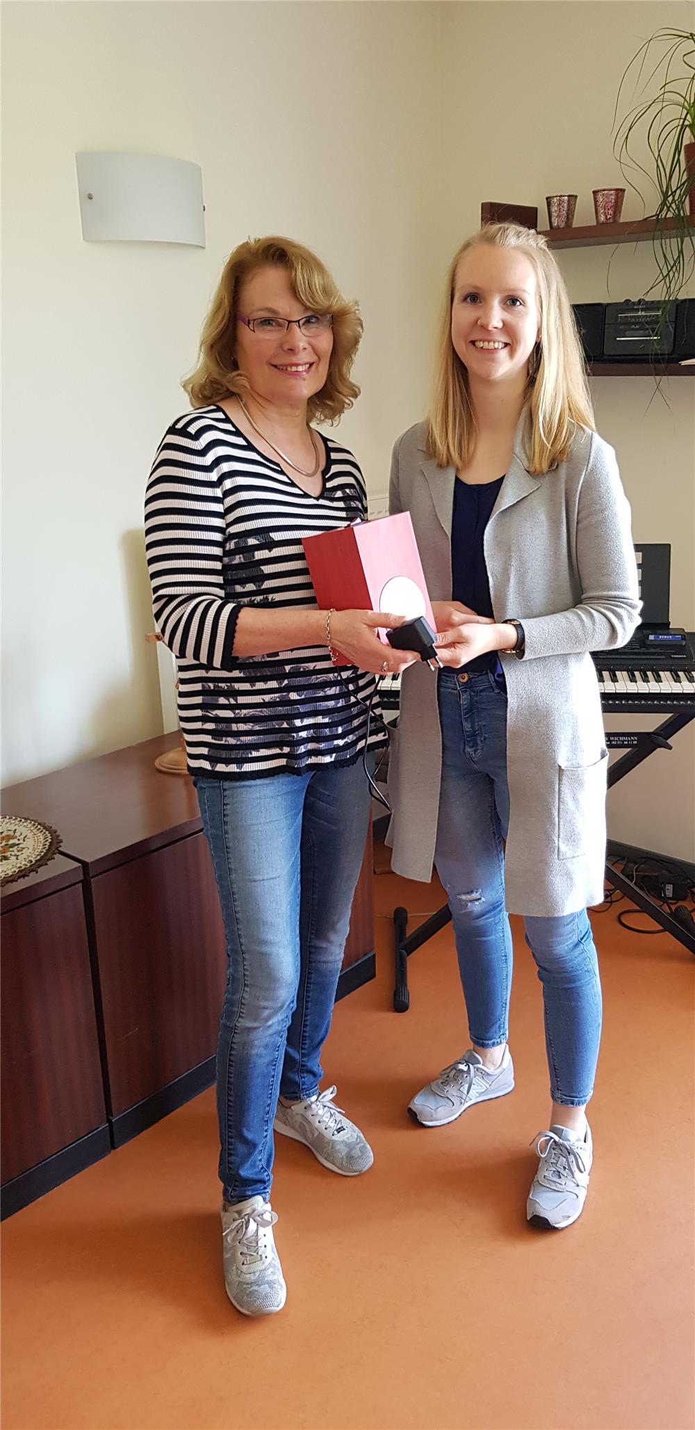 Das Bild zeigt zwie Damen mit einem Musiksystem.