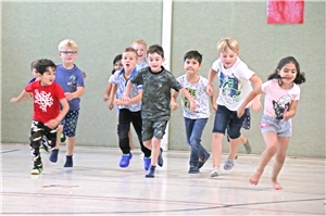 057-2019 GedankenSprung Eine Gruppe von Kindern in Sportkleidung setzt aufgeregt zum Rennen an