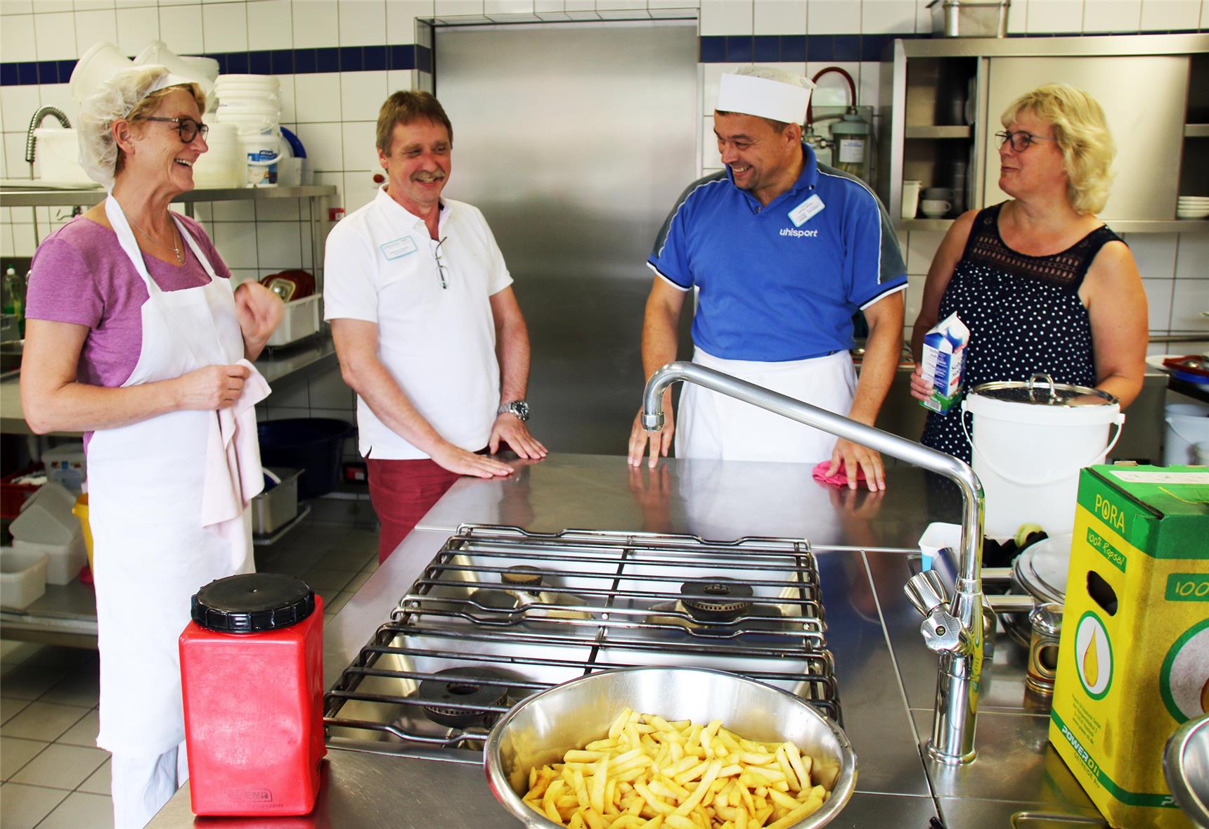 Vier Personen stehen in einer Großküche am Herd. 