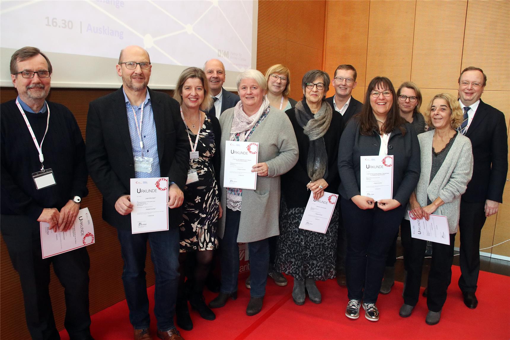 Eine Gruppe steht fröhlich mit Urkunden in der Hand.