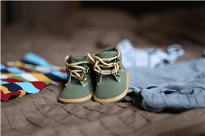 023-2020 Schwangerschaftsberatung Bocholt Das Foto zeigt ein Paar Babyschuhe auf einem Bett.