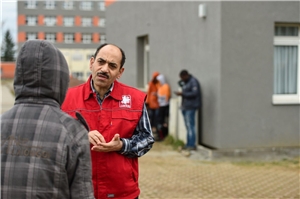 047-2020 ZUE Das Foto zeigt einen Caritas-Mitarbeiter im Gespräch mit einem Flüchtling.