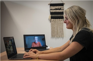 065-2020_Webinar_bistumsübergreifend Das Foto zeigt eine junge Frau vor dem Bildschirm und auf einem Laptop daneben.