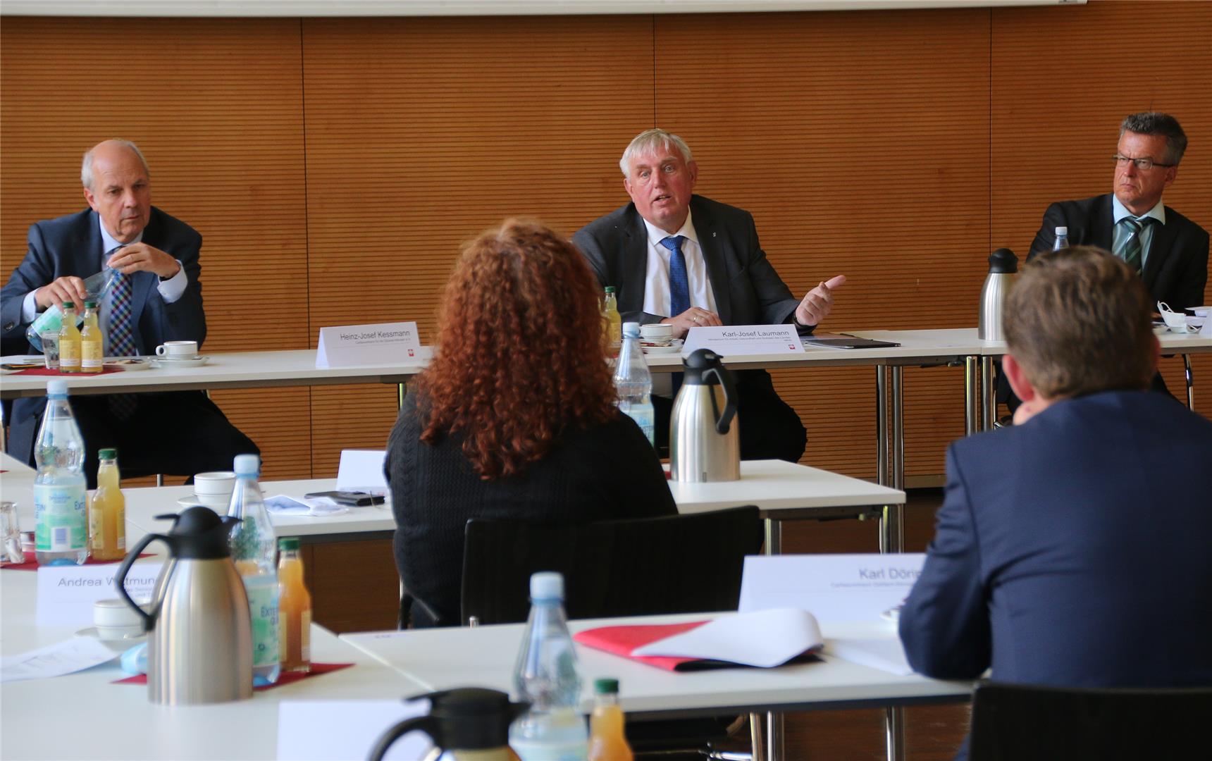 Das Foto zeigt drei Personen an einem langen Tisch. 