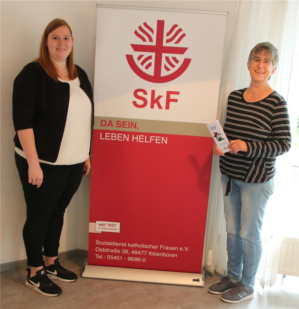 Zwei Frauen stehen neben einem Roll-up, welches das Logo des Sozialdienst katholischer Frauen zeigt.