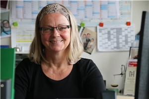 072-2020_Pflegekinder_Ahlen Eine Frau sitzt lächelnd am Schreibtisch.